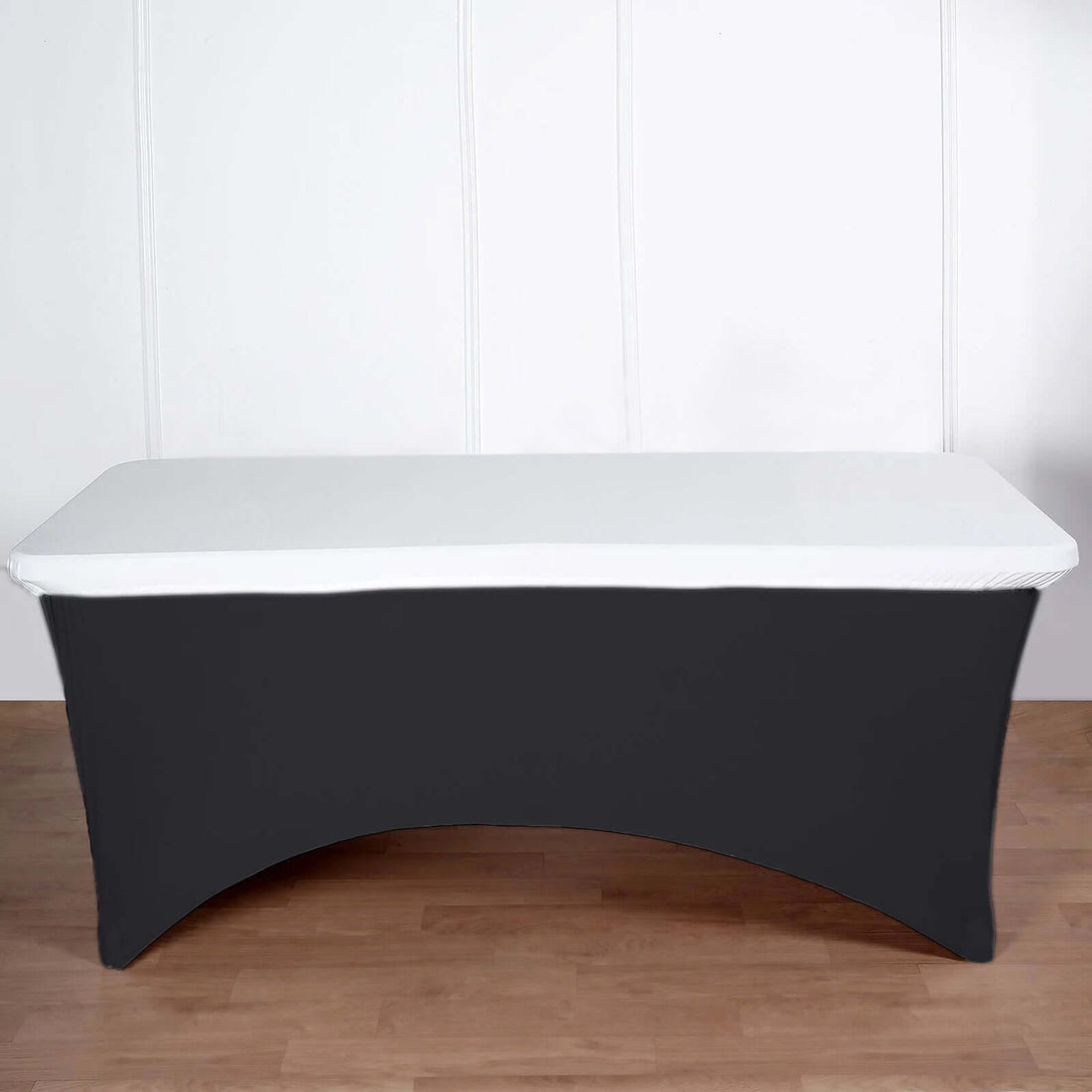 Black table cover with white top on a wooden floor.