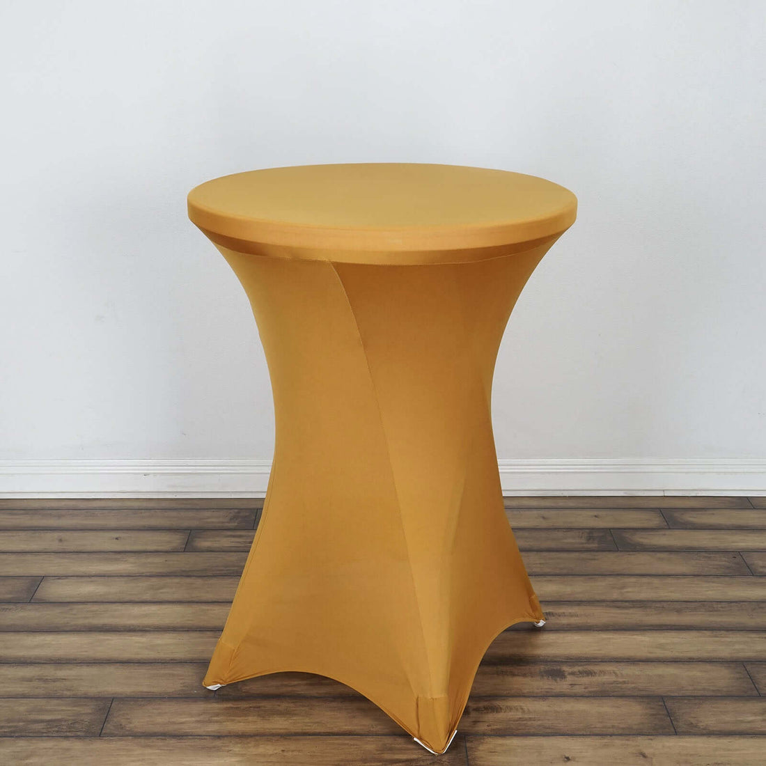 Yellow stretch table cover on a round table against a plain backdrop.