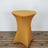 Yellow stretch table cover on a round table against a plain backdrop.