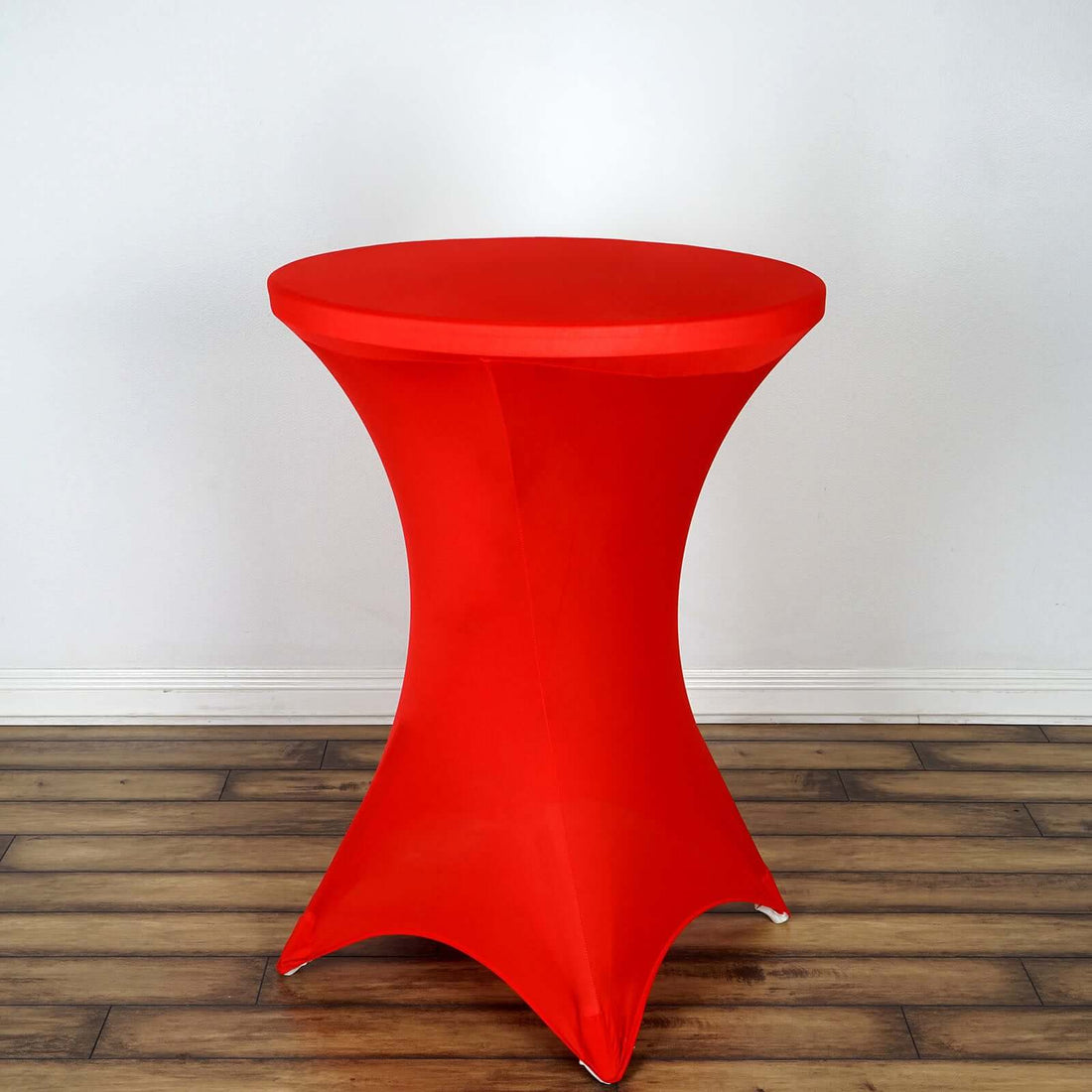 Red stretch table cover on a round table against a plain backdrop.