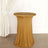 Gold stretch table cover on a round table against a plain backdrop.