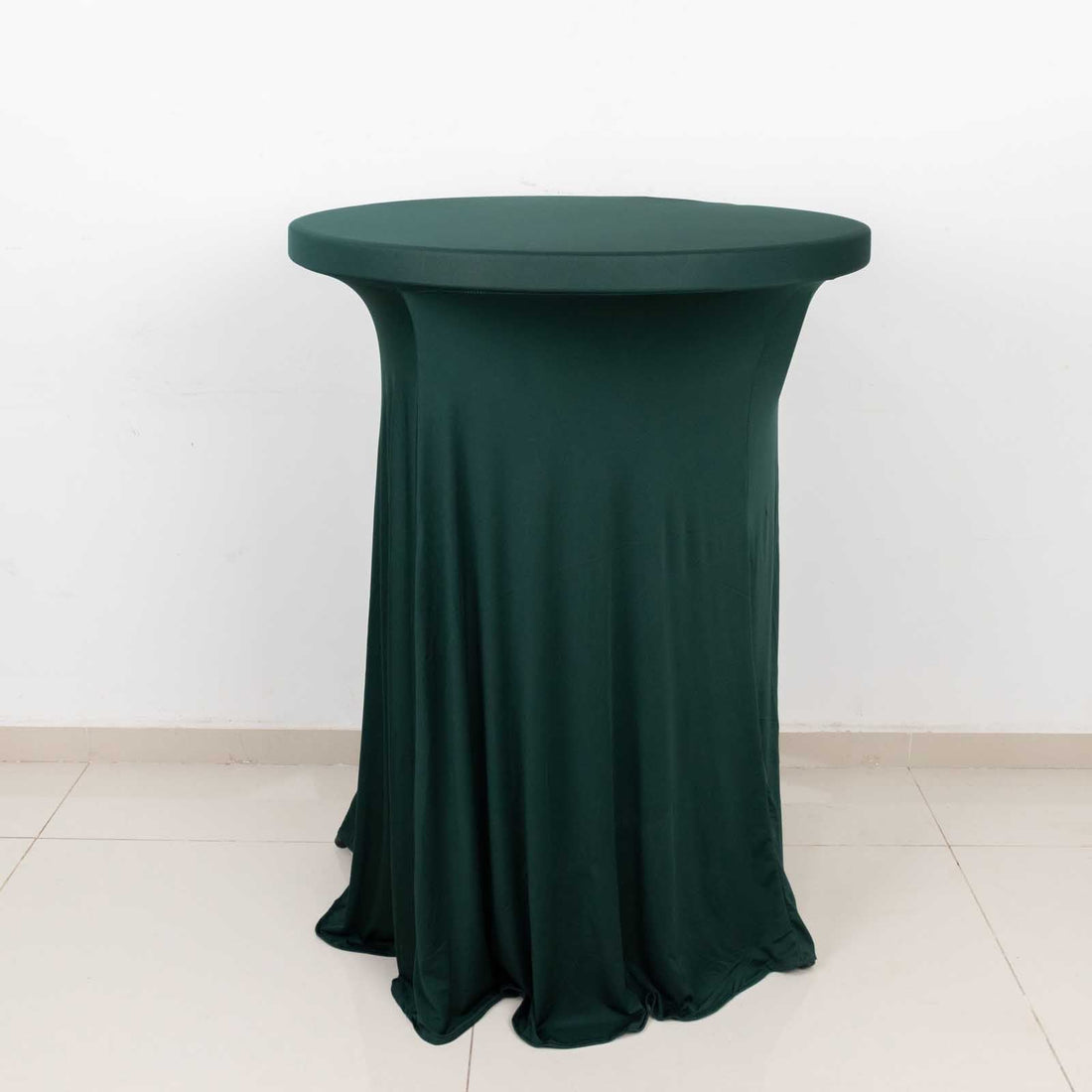 Green fitted table cover on a round table against a plain background