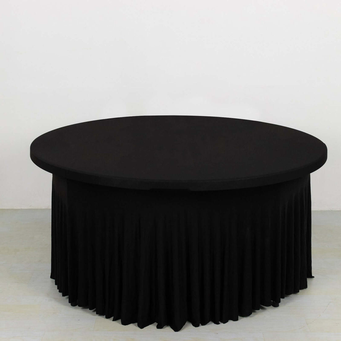 Black round table with pleated skirt, studio shot.