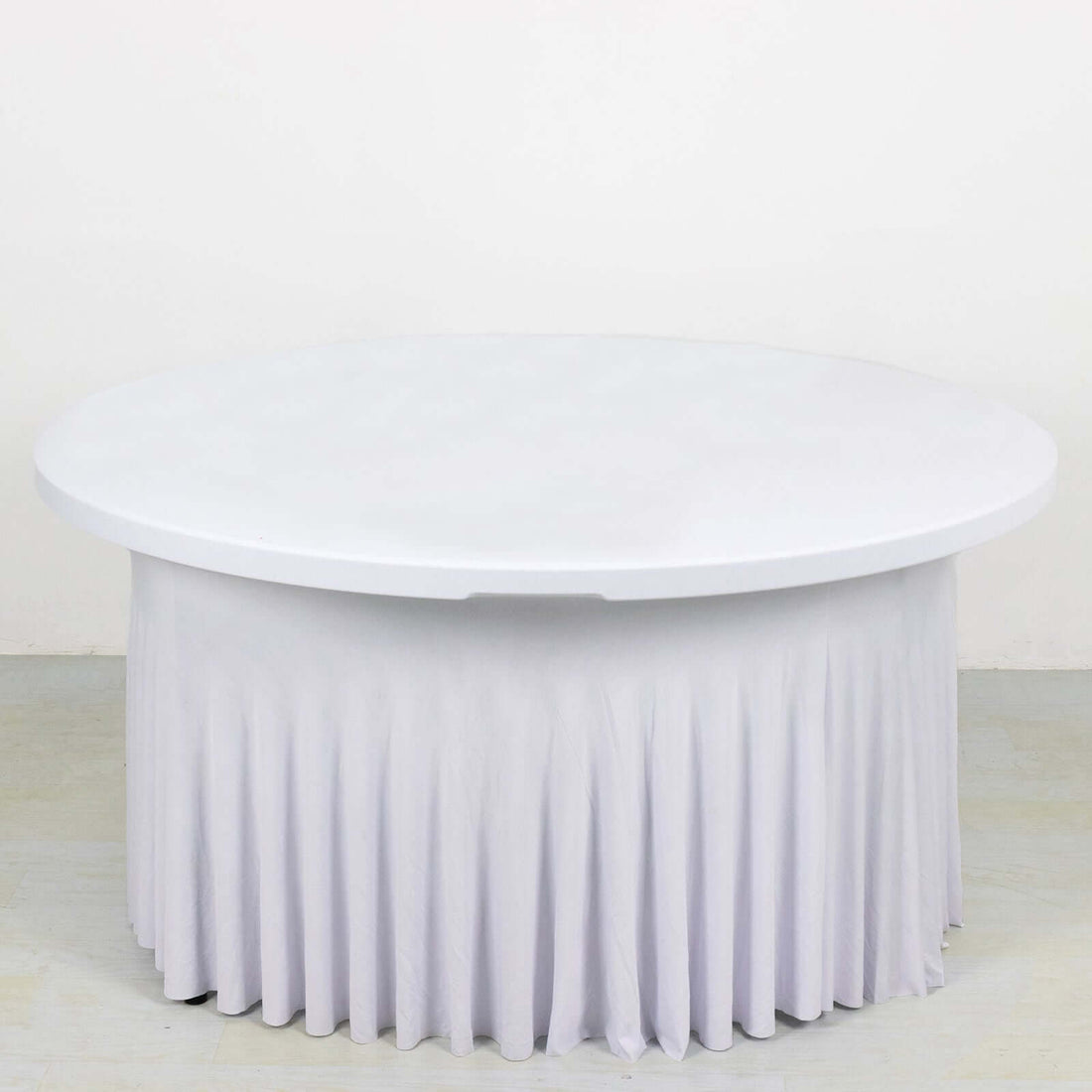 Round table with white draped skirt on plain background