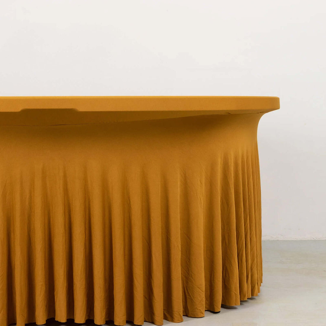 Yellow pleated tablecloth draped over a table against a plain backdrop.