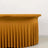 Yellow pleated tablecloth draped over a table against a plain backdrop.