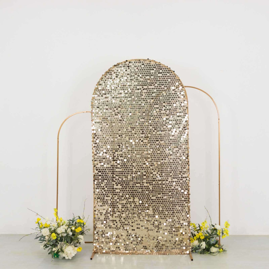 Gold sequin backdrop with floral arrangements, perfect for events and photo sessions.
