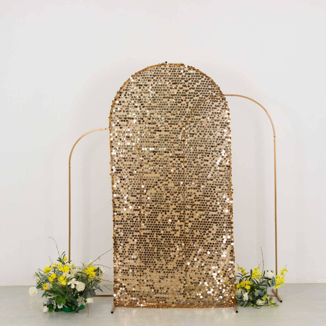 Gold sequin backdrop with floral arrangements on each side.