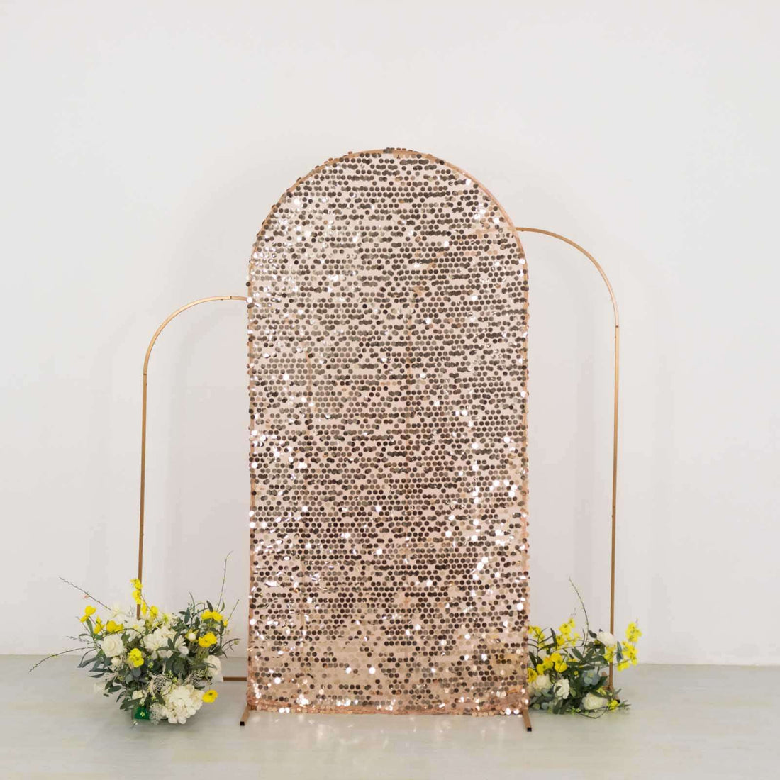Rose gold sequined backdrop with floral arrangements.