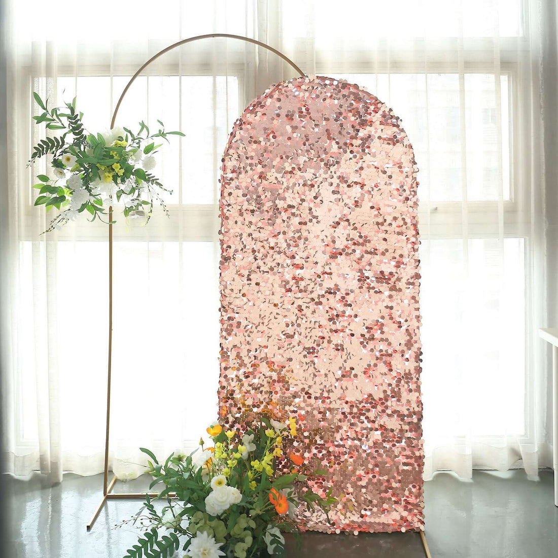Rose gold sequin backdrop with floral accents for events and photo shoots.