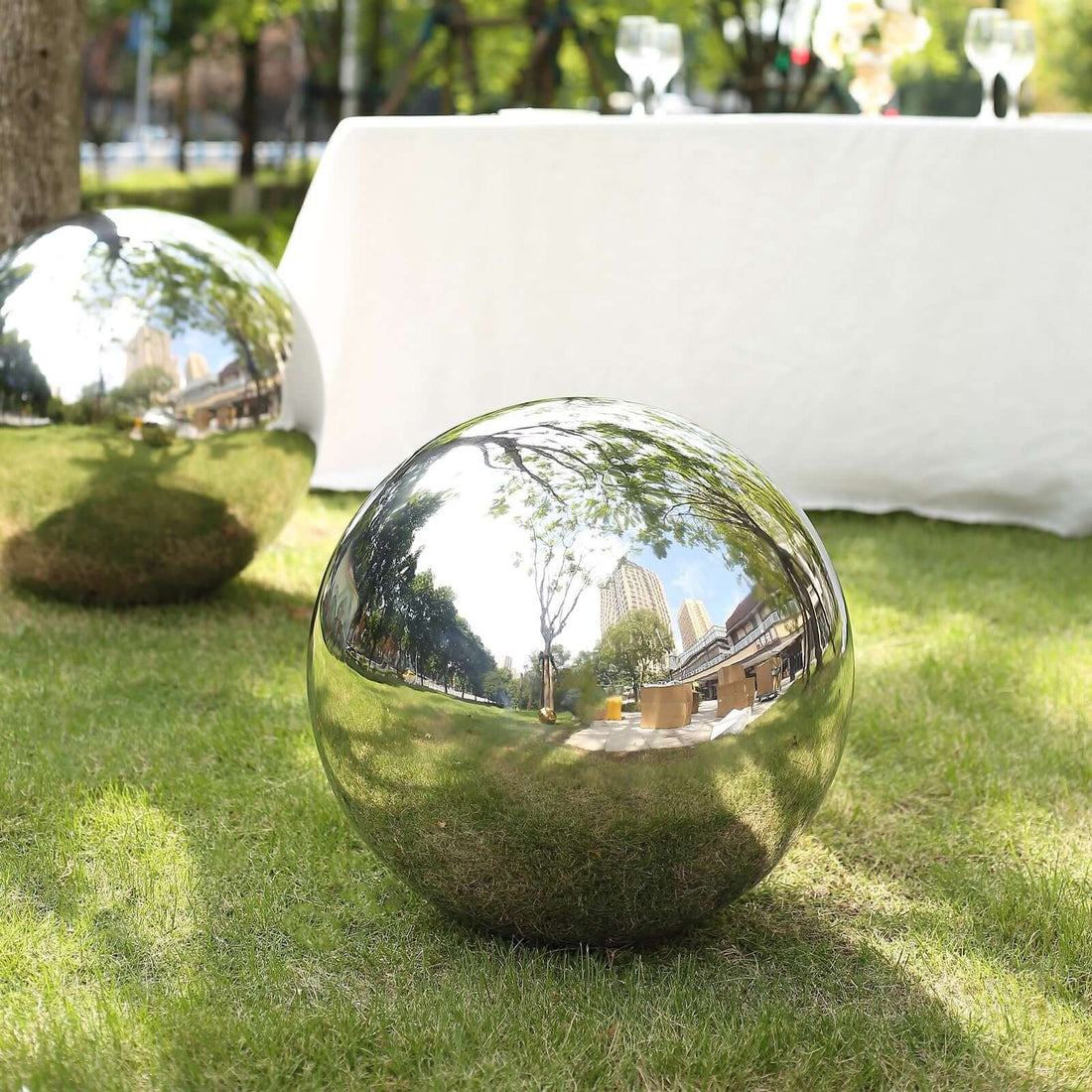 Reflective stainless steel garden orb on grass, showcasing outdoor ambiance.