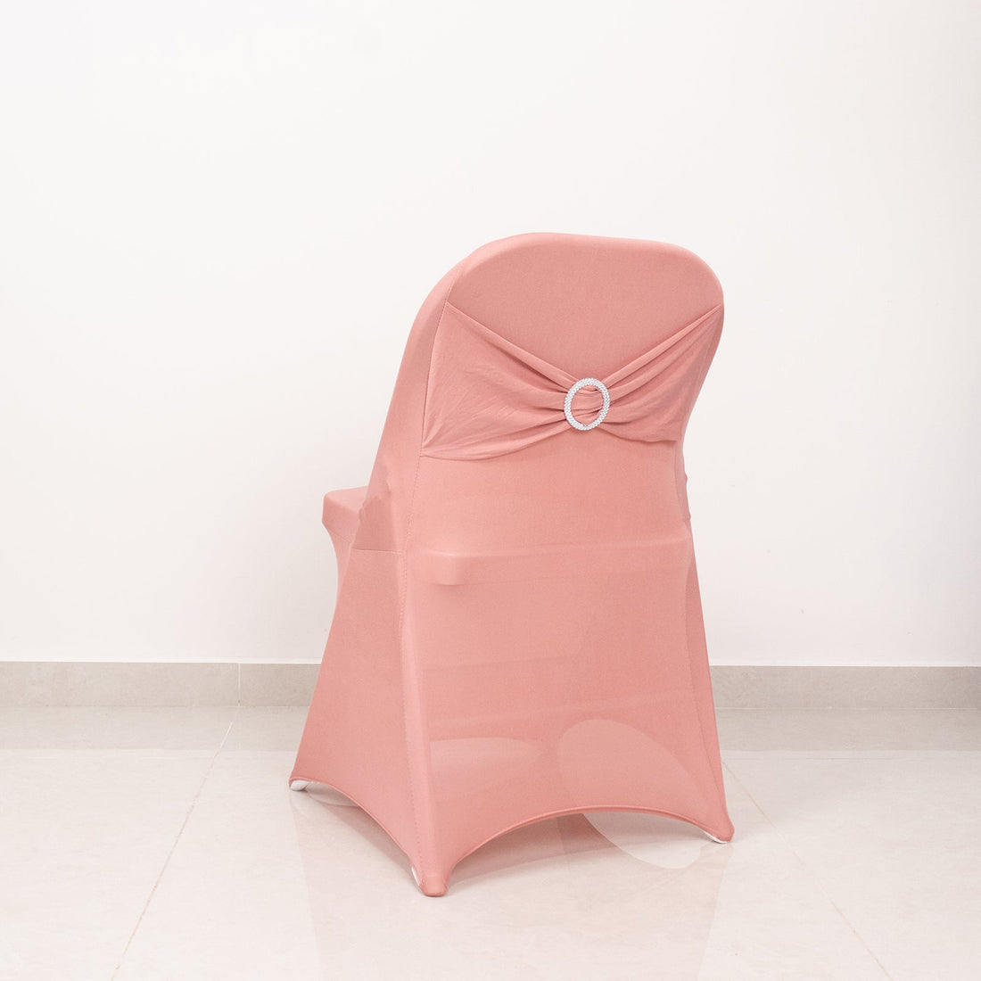 Pink chair cover with decorative ring detail on a plain backdrop.