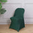 Green modern chair on a wooden floor with plant backdrop.
