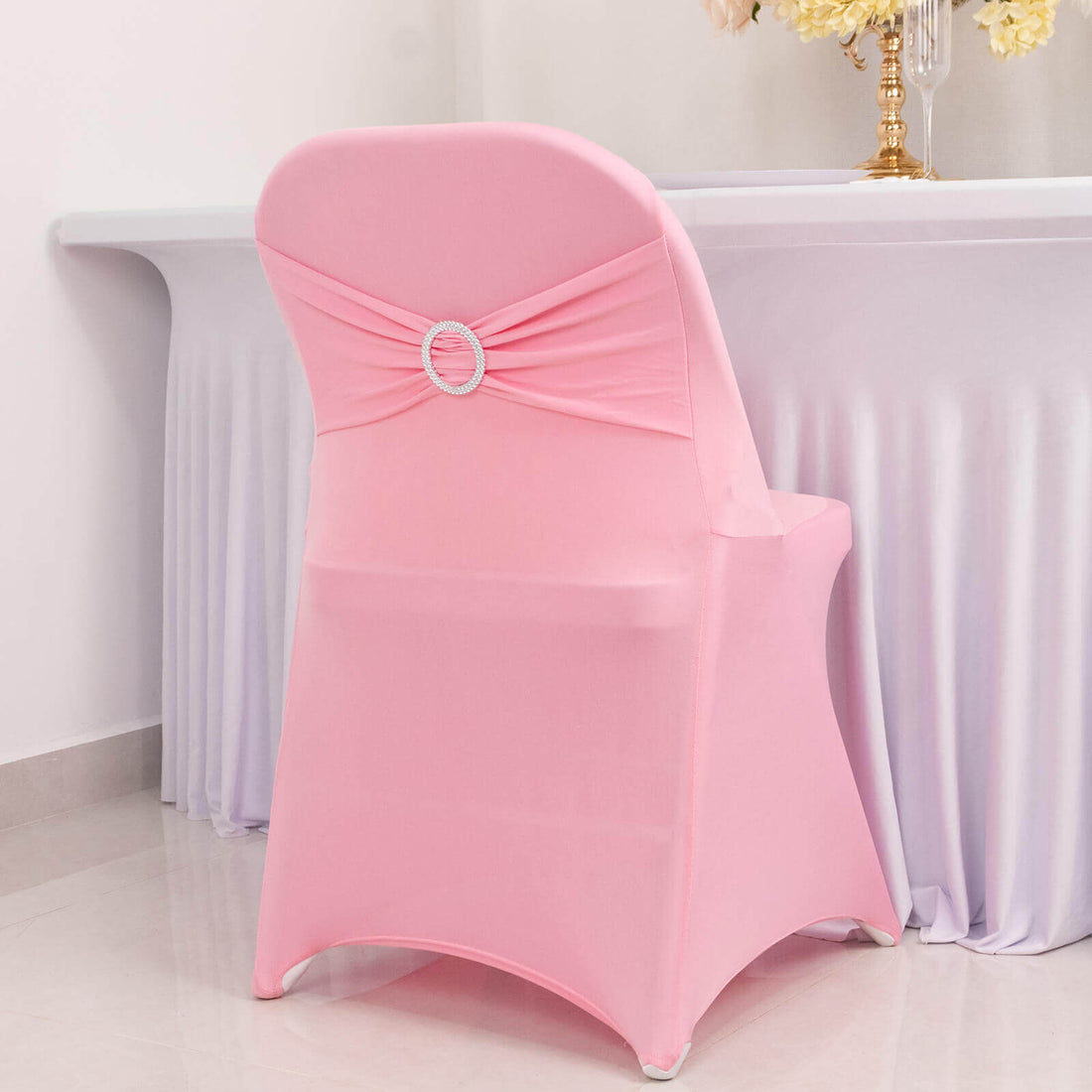 Pink chair cover with decorative bow for event seating.