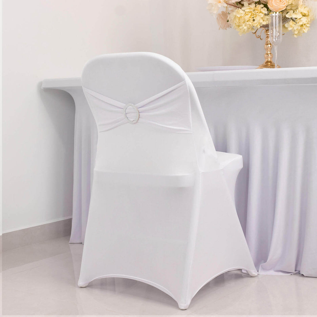 Elegant white chair cover with decorative back detail for events.