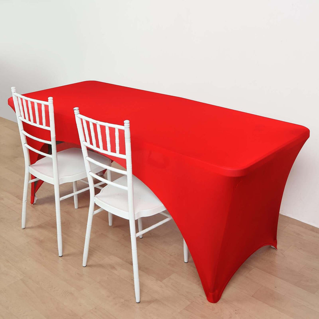 Red table cover draped over a table with white chairs in a plain setting.