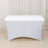 White table with fitted cover on a plain backdrop.