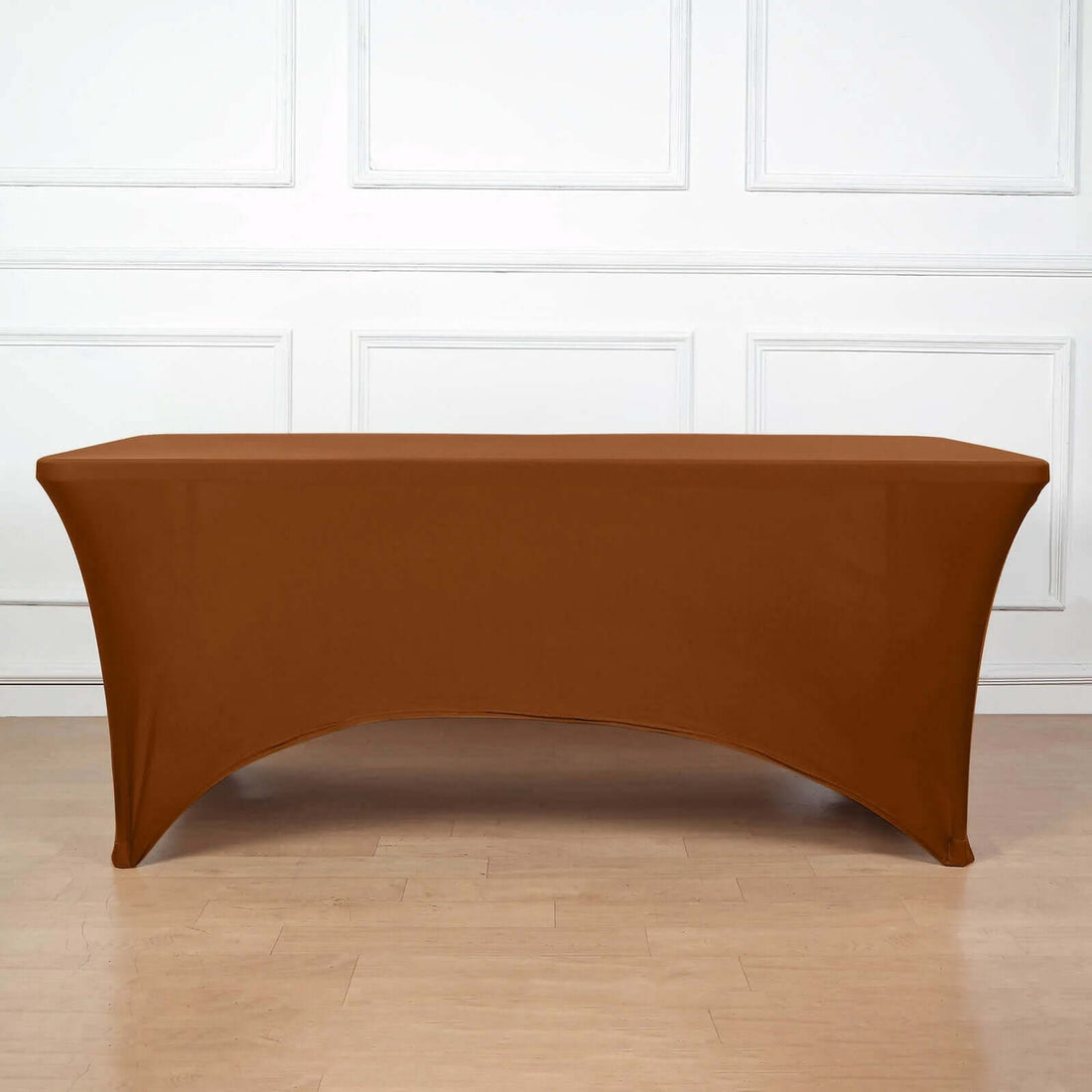 Brown stretch table cover on a wooden floor with a white backdrop.