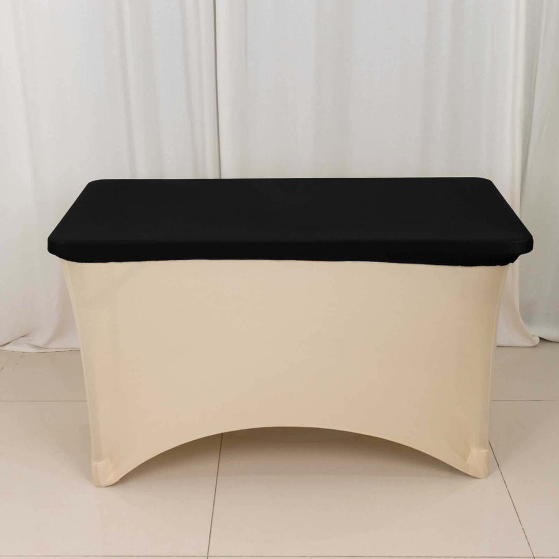 Black table cover on a beige table, suitable for events or displays.