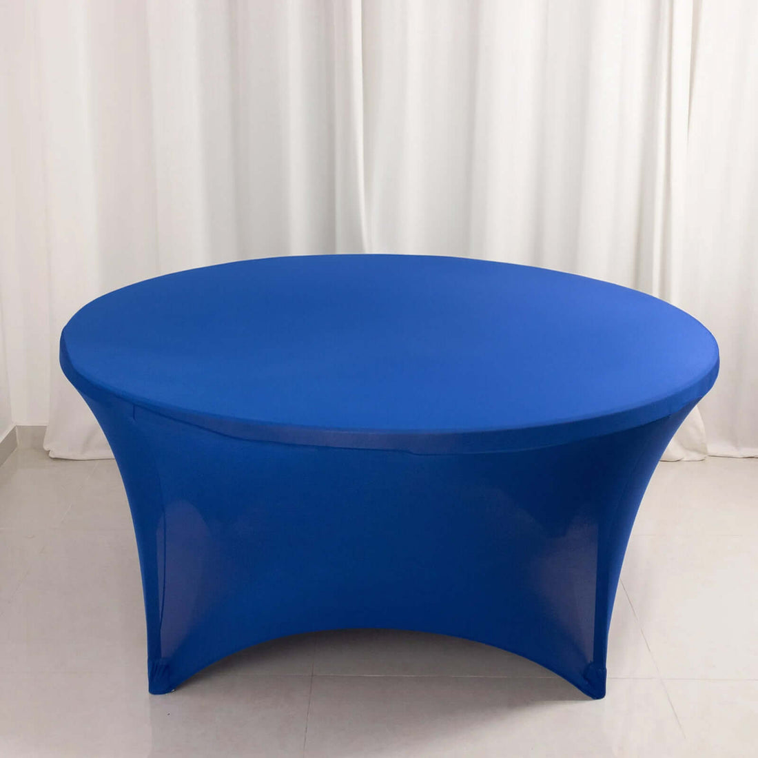 Blue stretch table cover on an oval table against a plain background.