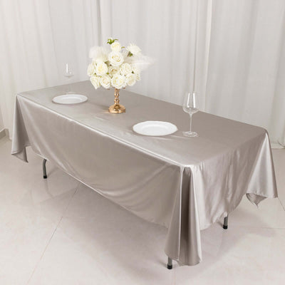 Elegant silver tablecloth with floral centerpiece and dinnerware set.