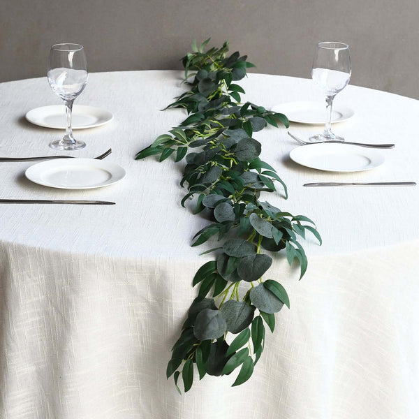 Elegant table setting with green foliage centerpiece and dinnerware.