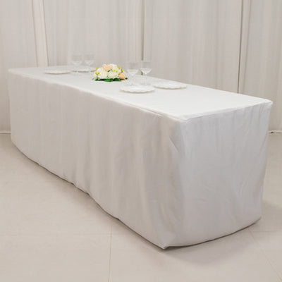 White table with draped linen, set for dining with plates and glasses.