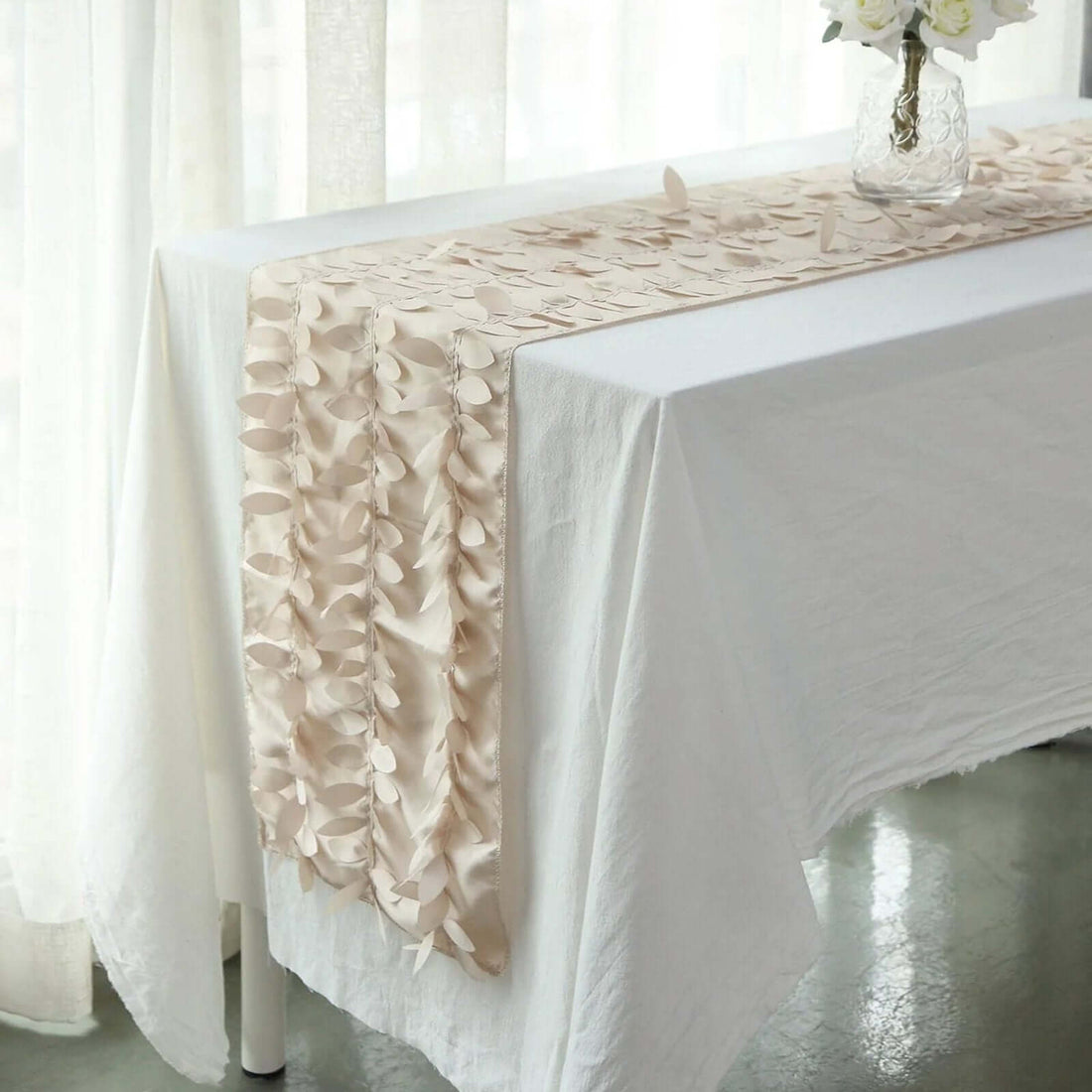 Elegant beige table runner with textured leaf design on a white table.