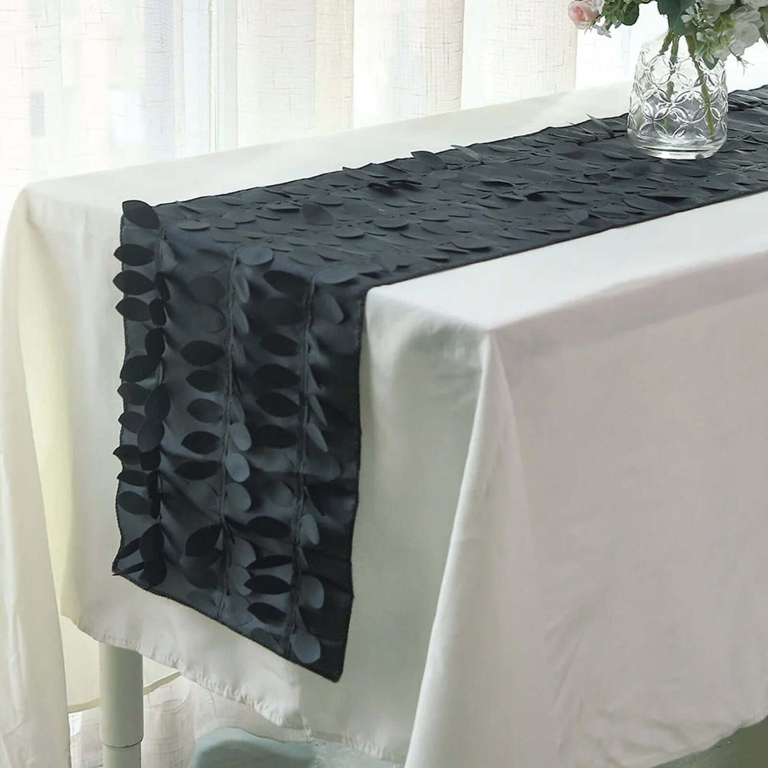 Black leaf-patterned table runner on a white tablecloth.