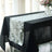 Elegant white table runner on a black table with a vase of flowers.