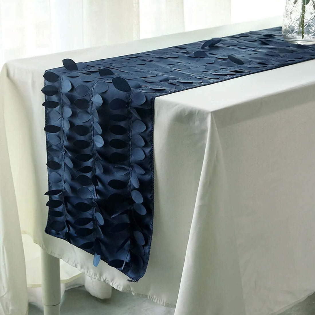Navy blue table runner with leaf design on a white tablecloth.