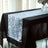 Elegant white and black table runner with leaf design on a dining table.