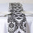 Black and white damask table runner on a dining table with glassware and plates.