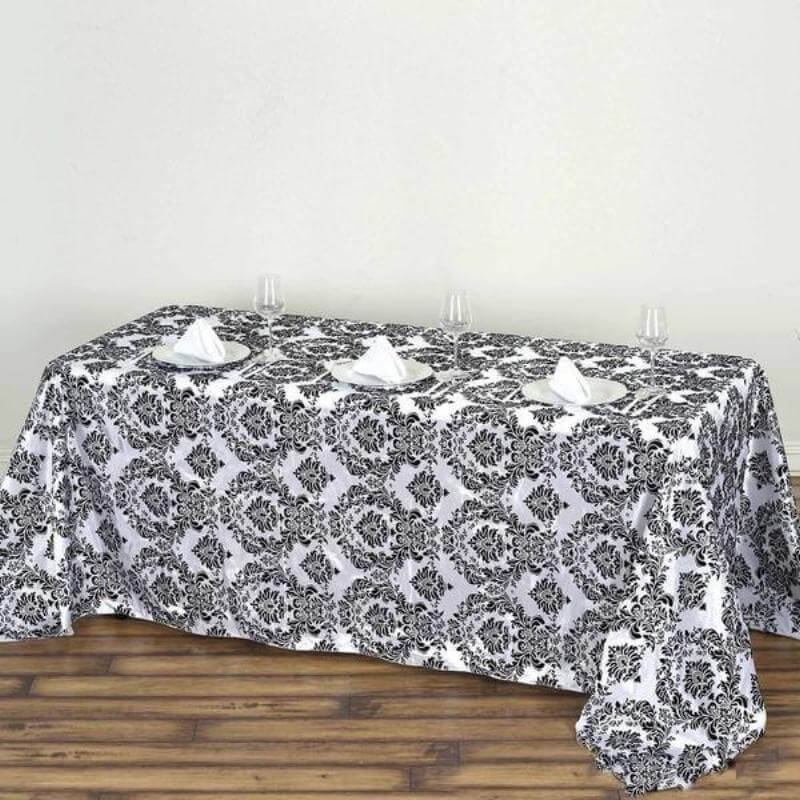 Black and white patterned tablecloth on a wooden table with plates and napkins.