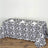 Black and white patterned tablecloth on a wooden table with plates and napkins.