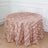 Pink leaf-patterned tablecloth draping over a round table in a styled setting.