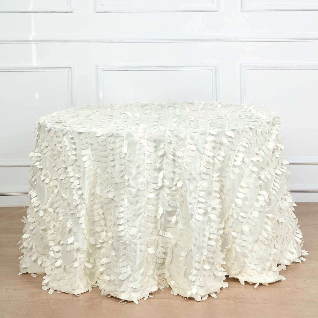 White tablecloth with leaf design draped over a round table