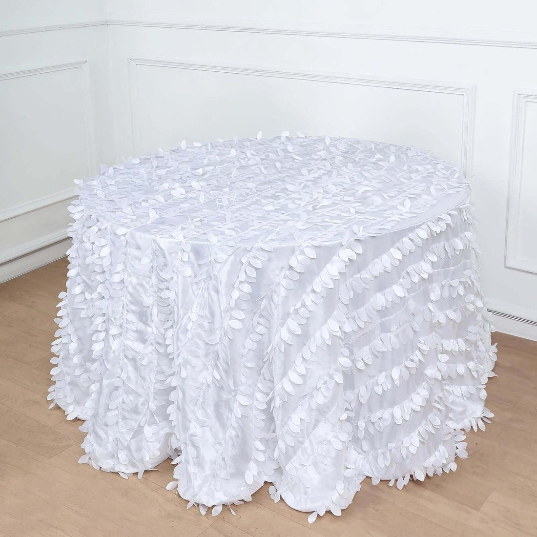 White tablecloth with leaf design draping over a round table
