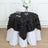 Black tablecloth with leaf design draped over a white table in a styled setting.