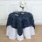 Navy blue leaf-pattern tablecloth draped over a white table with floral decor.