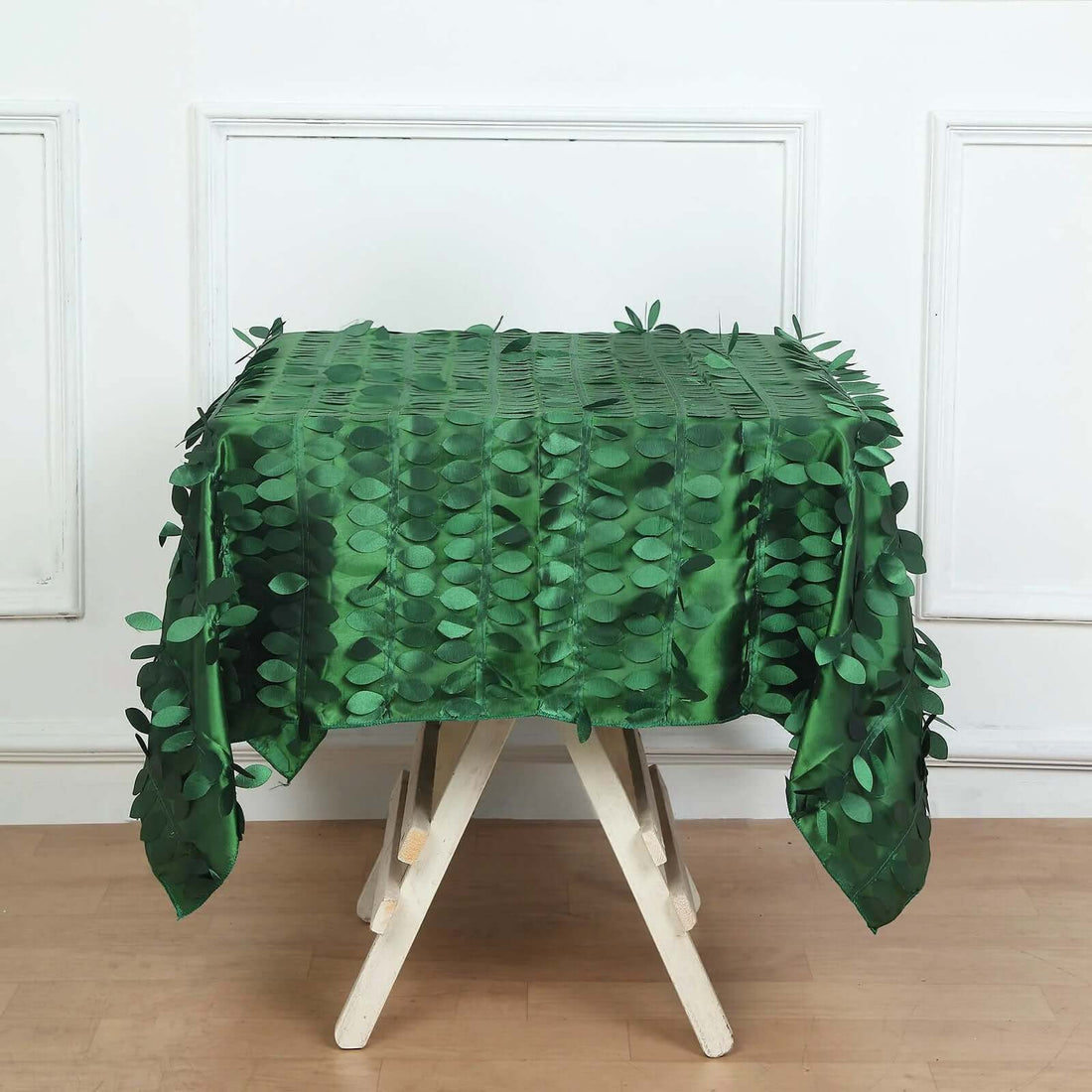 Green leaf-patterned tablecloth draped over a wooden table.