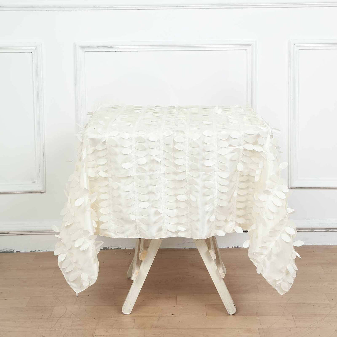 Textured white tablecloth draped over a wooden table in a studio setting.