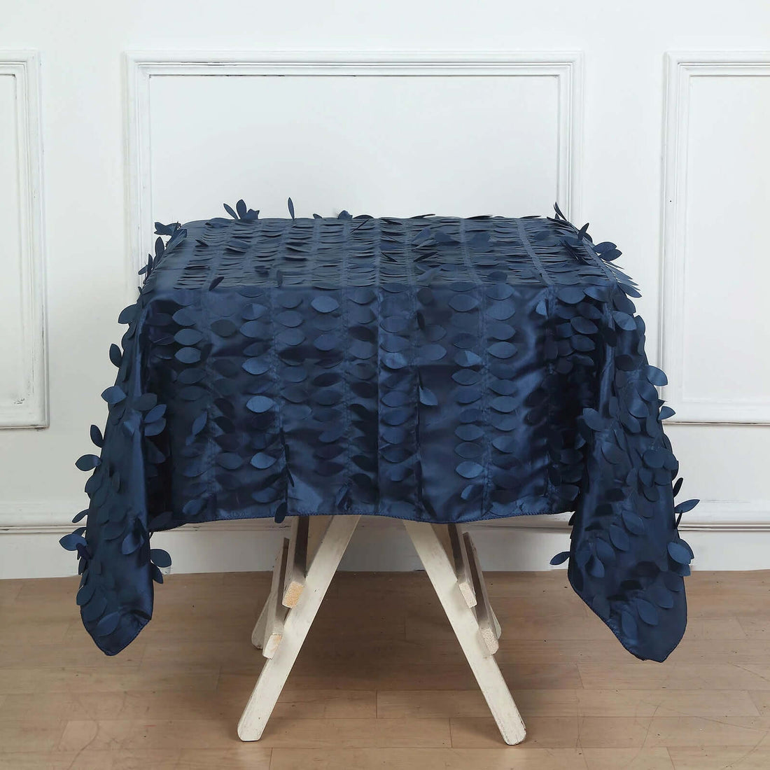 Navy blue leaf-pattern tablecloth draped on a white wooden table.