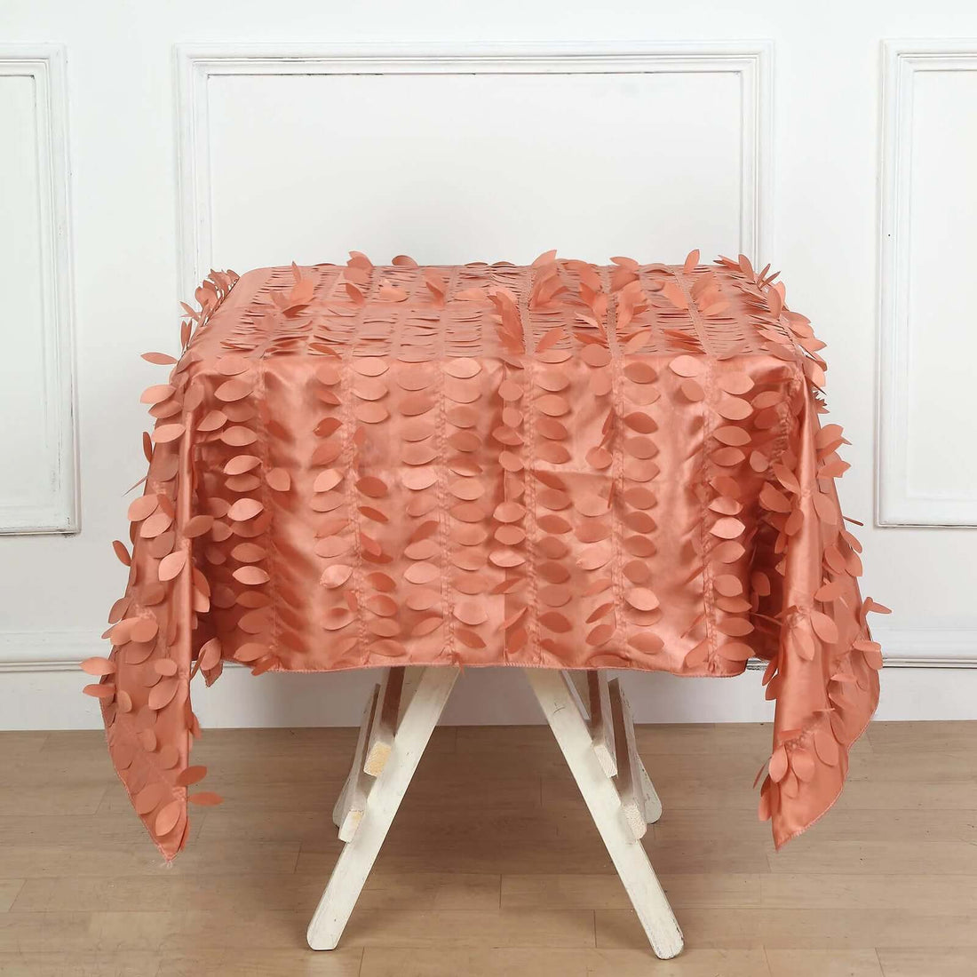 Peach leaf-patterned tablecloth draped over a white table.