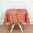 Peach leaf-patterned tablecloth draped over a white table.