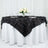 Black leaf-pattern table runner draped over a white table with flowers and glasses.