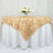 Gold leaf tablecloth draped over a round table with a floral centerpiece.