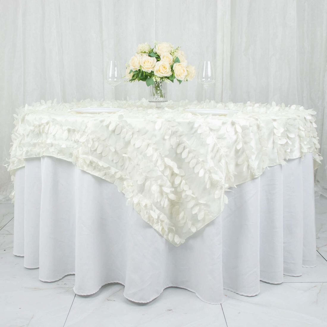 Elegant white tablecloth with floral design and centerpiece of roses.