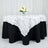 White floral tablecloth draped over a black table with a floral centerpiece.