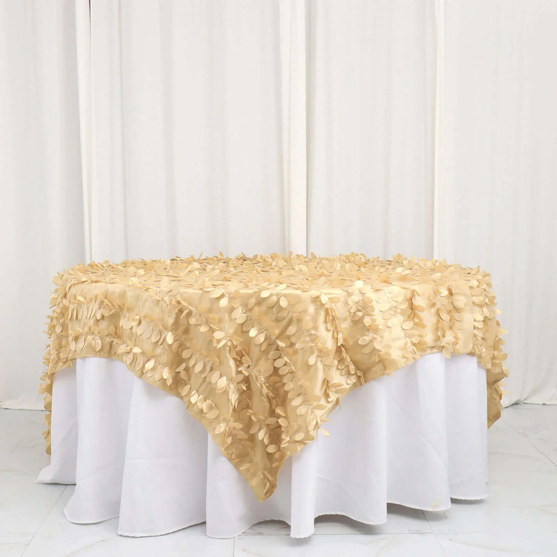 Gold leaf tablecloth draped over a round table in a studio setting